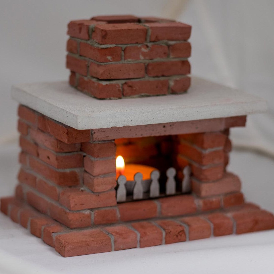 Realistic Mini Fireplace candle holder with lighted candle inside producing soft light