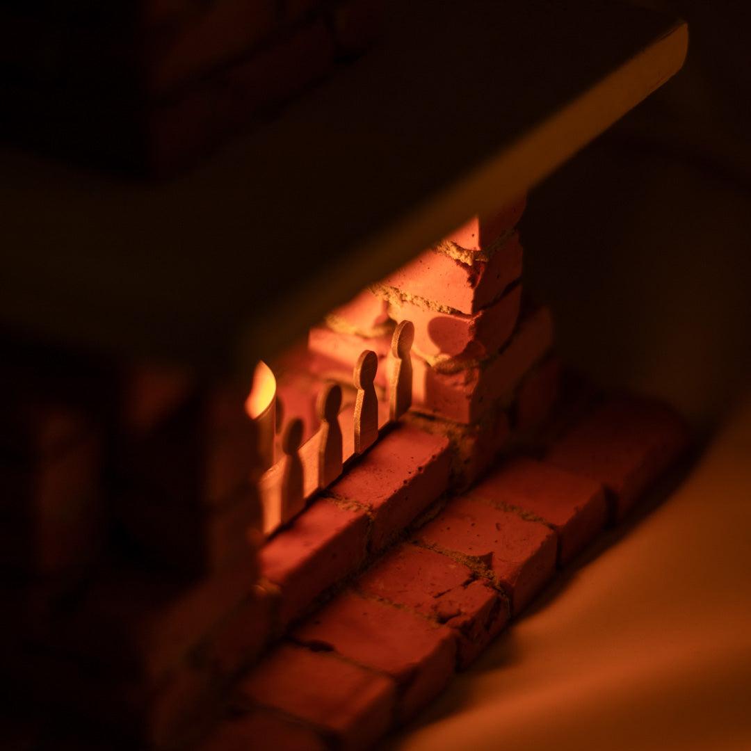 Top Edge view of a Miniature realistic fireplace with lighter tealight candle inside warming up an image